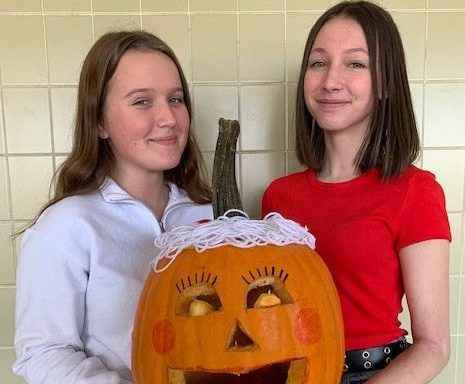 Morgann Clayworth and Elizabeth Hammontree hold their pumpkin. Their creation won in the category of "funniest."