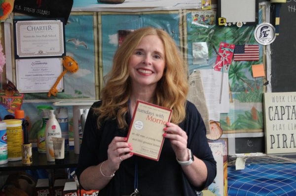 Ms. Hyder holding the book Tuesdays with Morrie. 